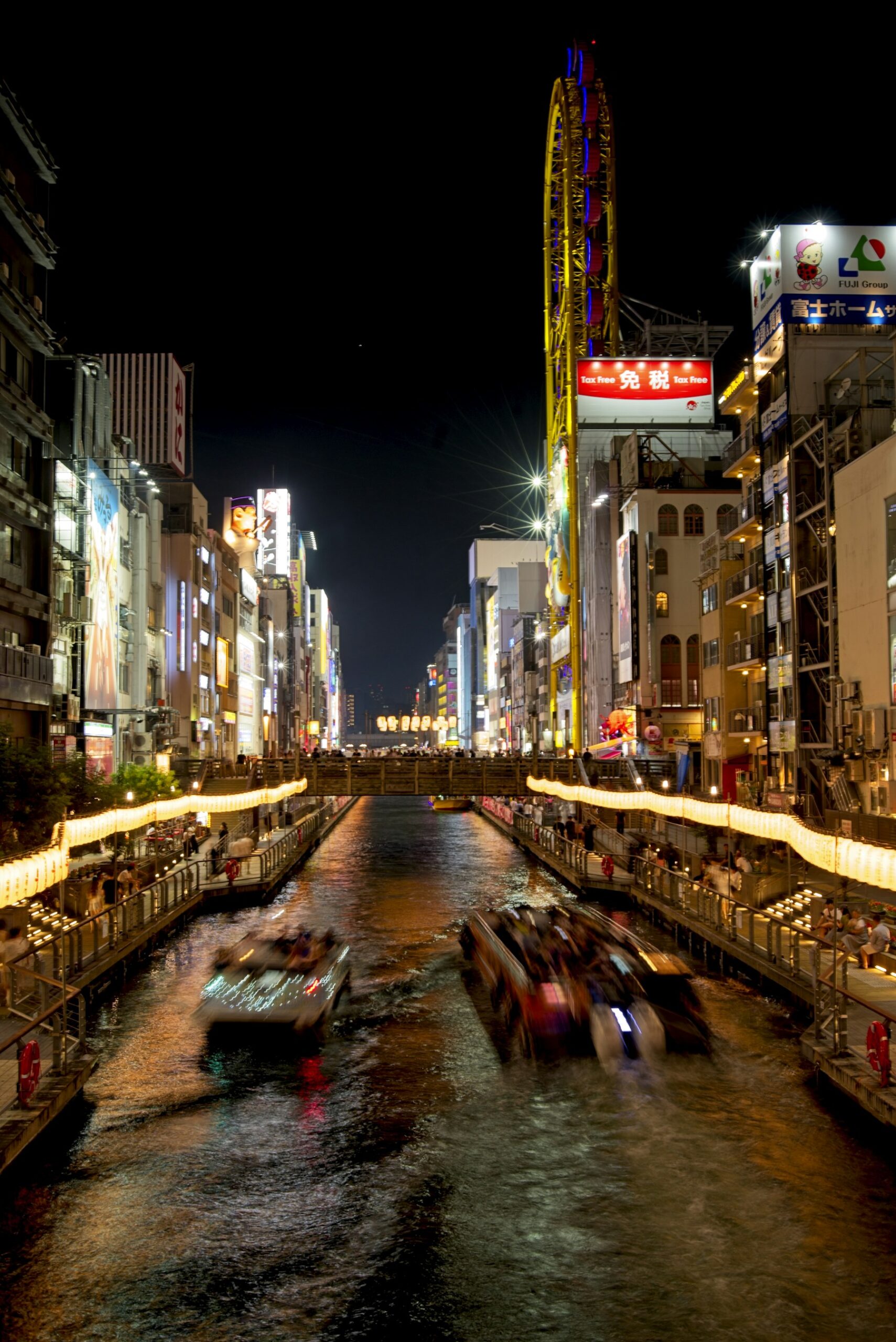 Tour boats on the illuminated Dotonbori Canal in Osaka at night