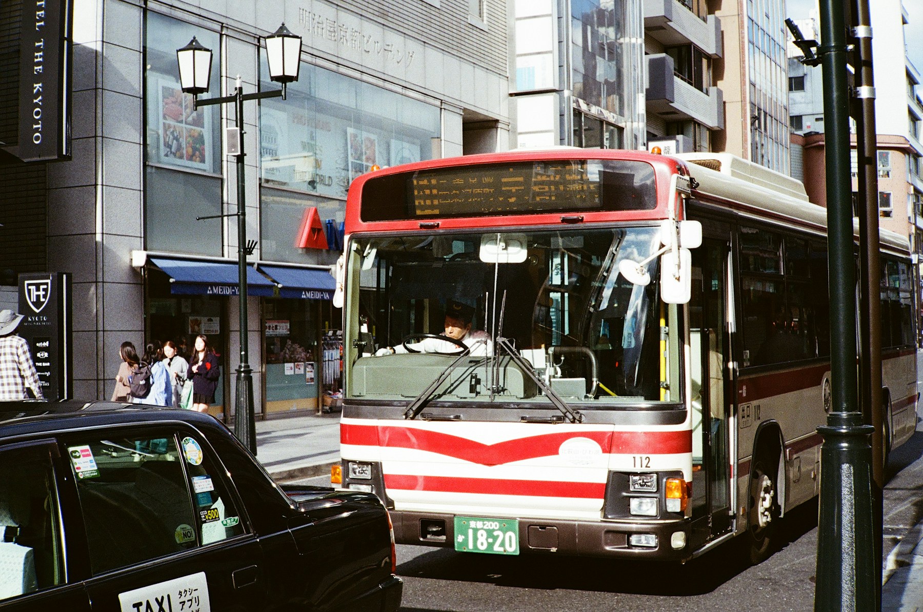 Kyoto city bus traveling along a busy urban street.