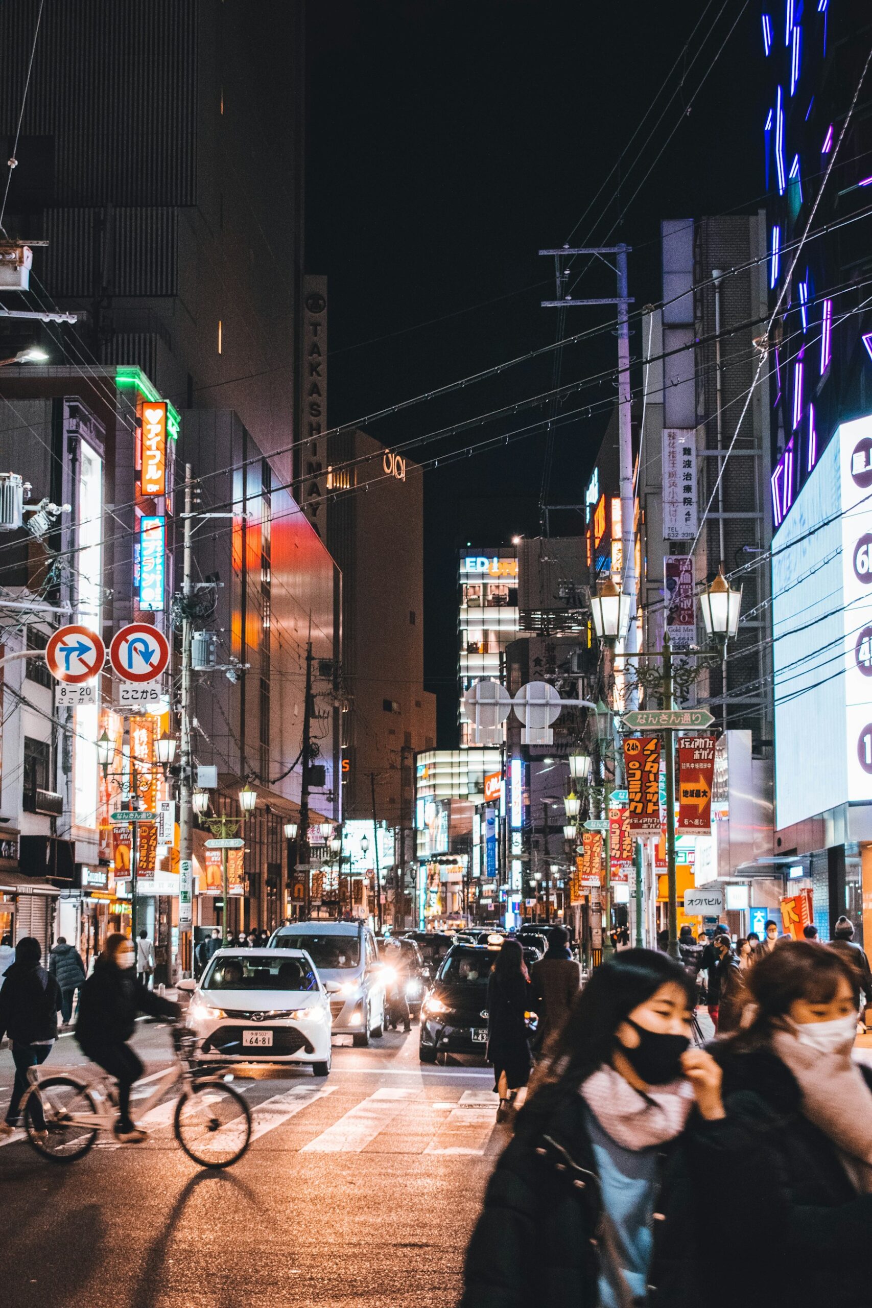 Travelers walking through illuminated Namba streets in Osaka at night