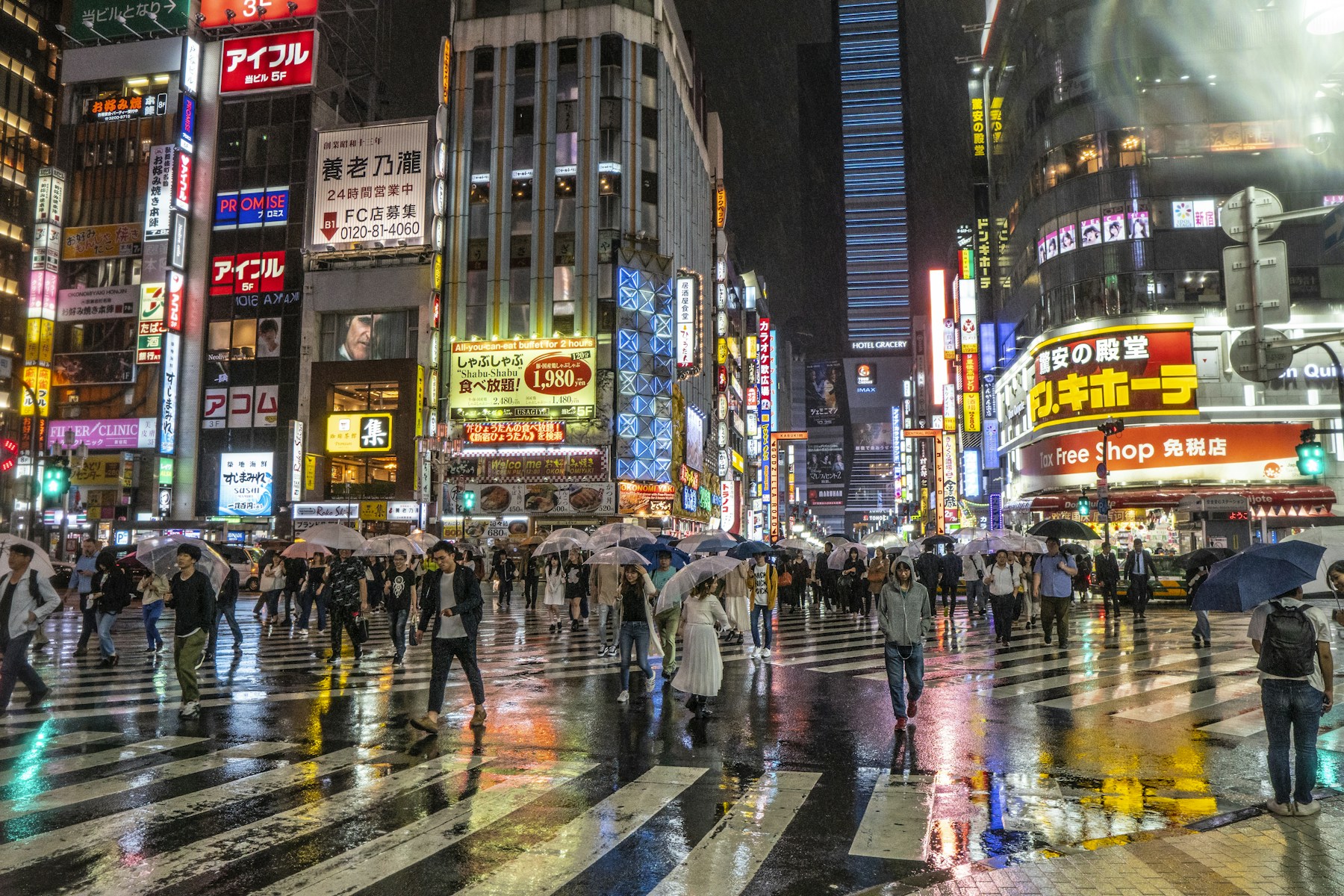 Crowds crossing a neon-lit street in Shinjuku, Tokyo