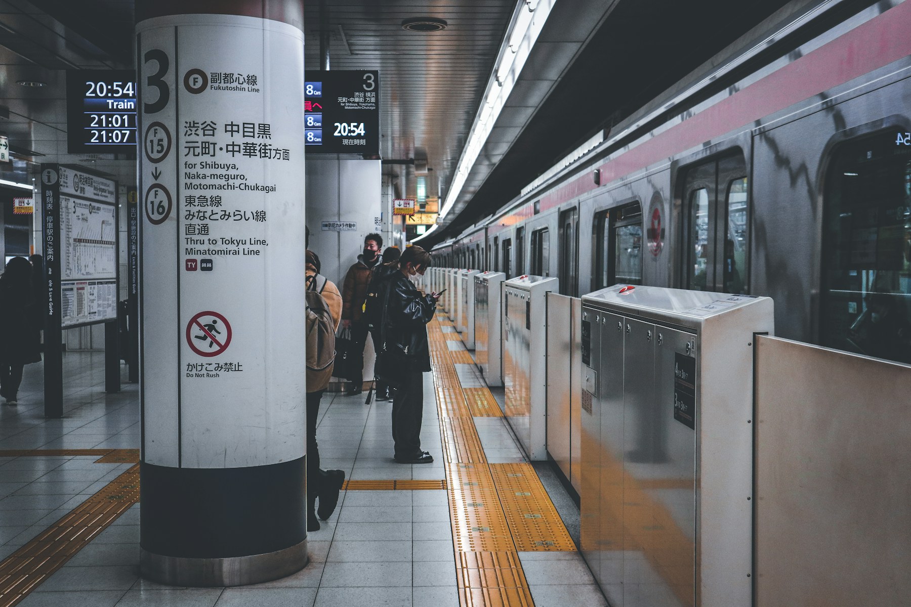 Passengers waiting beside a subway train at Omotesando station in Tokyo